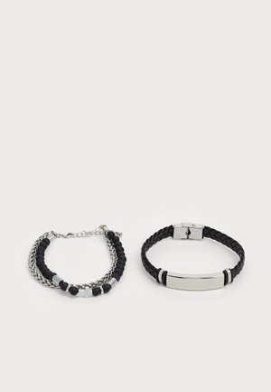 Deux bracelets : l'un avec des perles noires et des maillons en chaîne argentés, l'autre un style en cuir noir tressé avec un fermoir en plaque argentée.