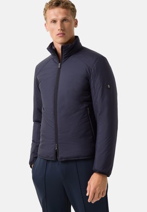 Marineblaue isolierte Jacke mit Stehkragen, Reißverschluss vorne, seitlichen Taschen und glattem Stoff. Mit einem Logo auf dem Ärmel.
