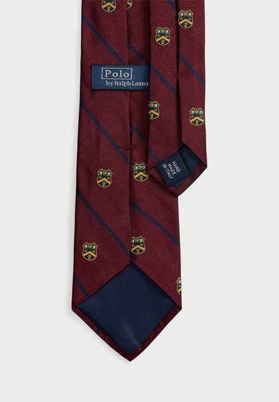 Gravata em bordô com riscas diagonais em azul marinho, adornada com motivos de escudo em dourado e azul. Fabricada em tecido texturizado com etiqueta feita à mão.