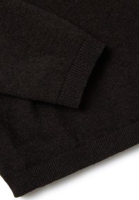 Manica di maglione lavorato a maglia marrone scuro con polsini e orlo a coste su una superficie bianca.
