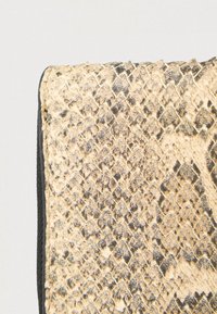 Tekstureret kunstigt slangeskindsmateriale i beige og sort mønster med en glat sort kant langs kanten. Rektangulær form.