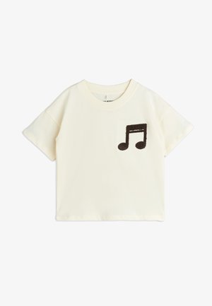 Kremfarvet kortærmet t-shirt lavet af blødt stof, med en fuzzy brun musiknote-applikation på fronten. Lige kant.