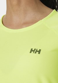Felgeel sportshirt gemaakt van textuurstof, met een ronde halslijn en een klein donker logo op de borst.
