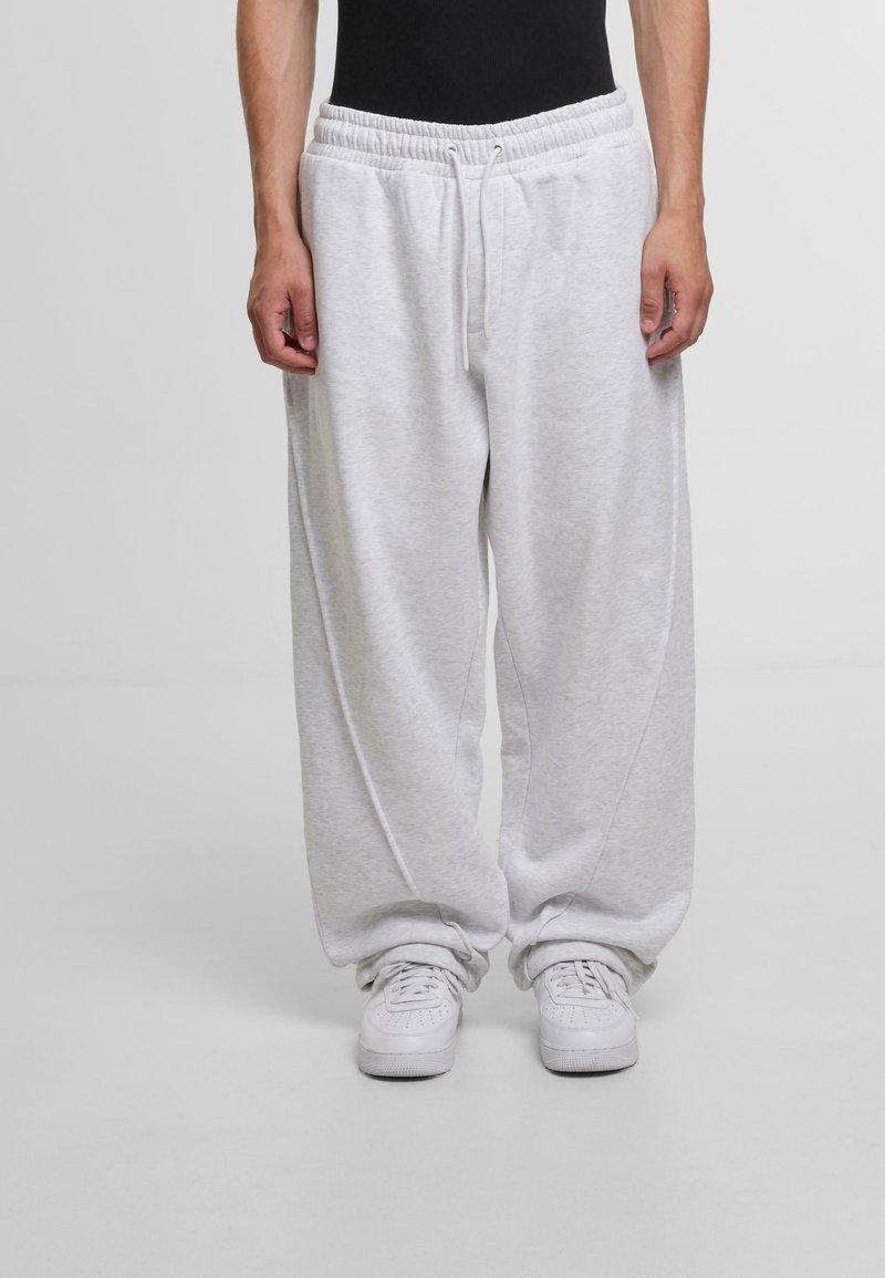 Light gray sweatpants with a loose fit, elastic waistband, adjustable drawstring, and side pockets; paired with white sneakers.