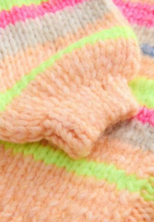 Detail eines gestrickten Pullovers mit pastellorange und rosa Streifen, akzentuiert mit limonengrünen Elementen. Die Textur ist weich und flauschig, was das grobe Strickmuster betont.