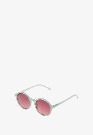 Lunettes de soleil rondes avec une monture transparente vert clair et des verres dégradés roses, dotées de branches fines pour un design léger.