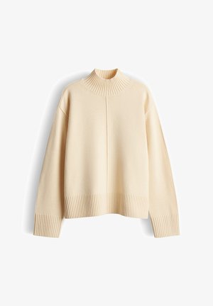 Crèmewitte coltrui gemaakt van zachte stof met een geribbelde textuur aan de kraag en zoom, met een losse pasvorm en verlaagde schouders.