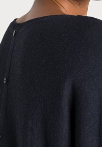 Maglione in maglia navy con una finitura texturizzata, ampio scollo e bottoni lungo la schiena. Materiale morbido con una vestibilità rilassata.