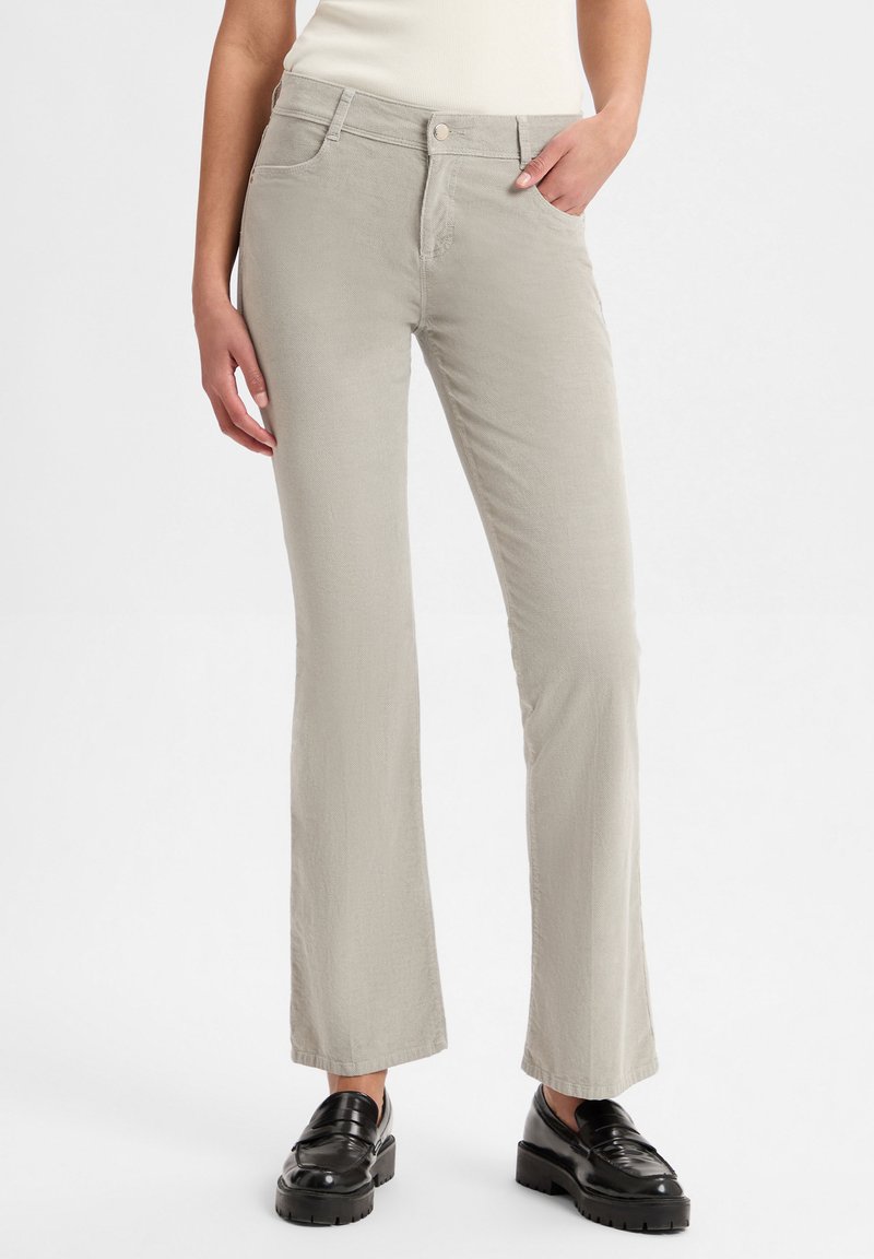 Lichtgrijze flared jeans met een zachte textuur, met voorzakken, riemlussen en een knoopsluiting, gecombineerd met zwarte platform loafers.