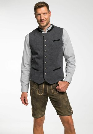 Dunkelgraue Wollweste mit abgerundetem Saum, silbernen Knöpfen und schwarzen Samt-Akzenten, kombiniert mit braunen Ledershorts mit gemustertem Näht.