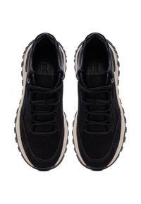 Scarpe sportive nere con parte superiore in suede e pelle liscia, leggera intersuola beige, suola in gomma nera spessa e lacci neri piatti.
