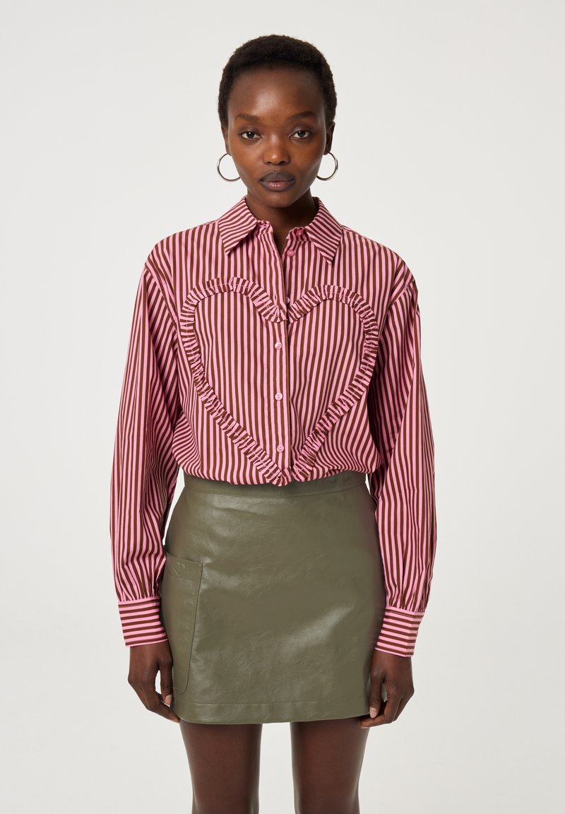 Gestreepte blouse met een hartvormige ruches in roze en bordeauxrood, gecombineerd met een aansluitende olijfgroene neplederen rok.