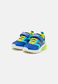 Baskets bleues et vertes avec une tige en maille, dotées d'une sangle velcro, de lacets jaunes contrastants et d'une semelle intermédiaire blanche avec un accent vert.