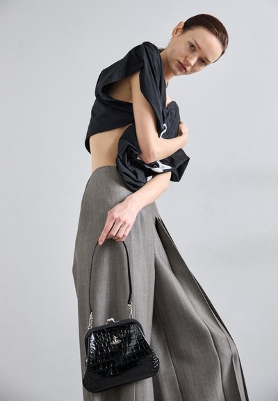Zwarte cropped shirt, grijze brede broek en een kleine zwarte handtas met krokodillenprint en een kort hengsel. Gelaagd en gestructureerd ontwerp.