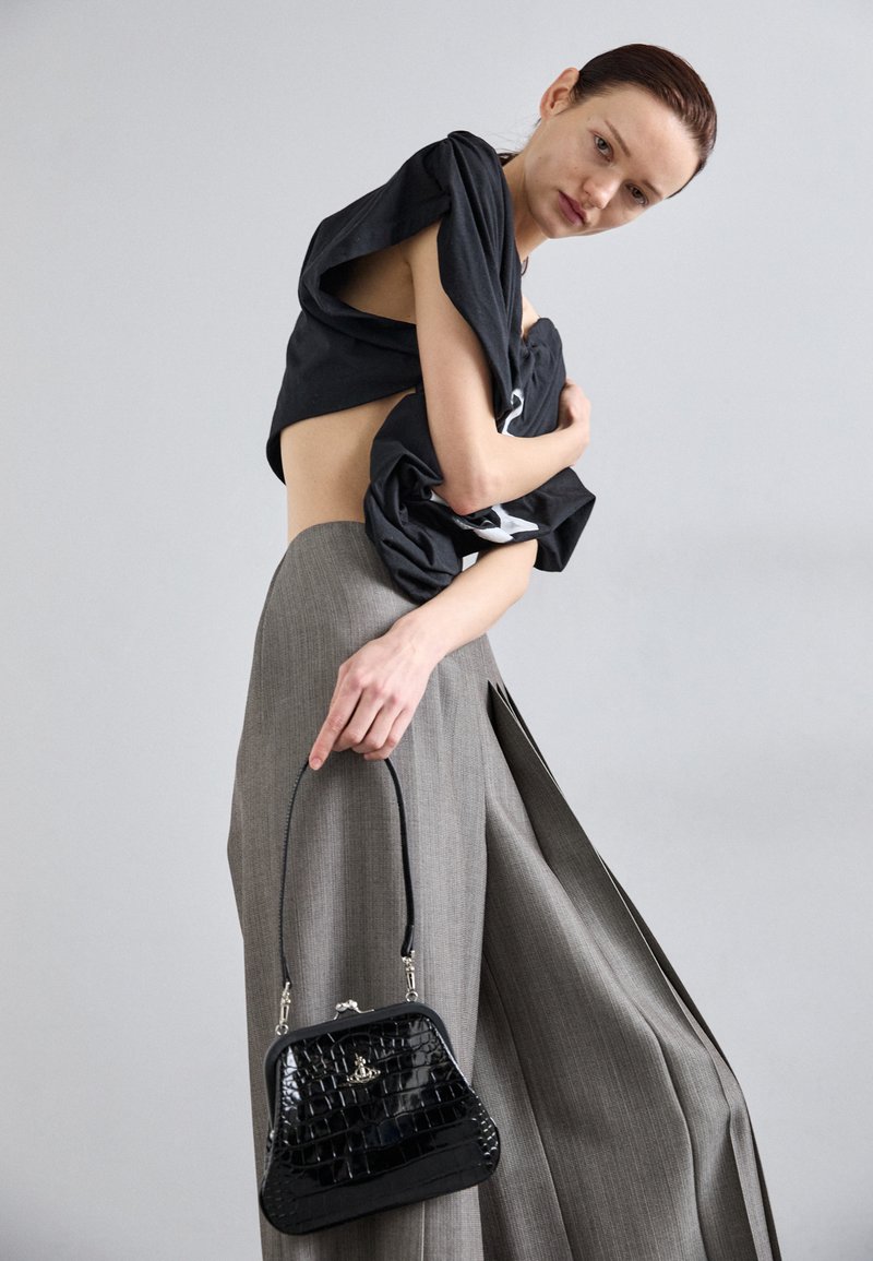 Black cropped shirt, gray wide-leg trousers, and a small black crocodile-embossed handbag with a short handle. Textured and structured design.