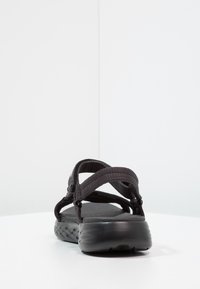 Sorte sandaler med stoffremmer og teksturert såle. Har justerbare lukninger og en chunky såle med et vevd mønster.