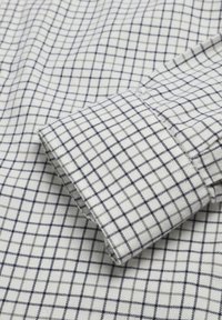 Cotton shirt with a white base and navy check pattern, featuring a double-button cuff and slightly textured fabric.