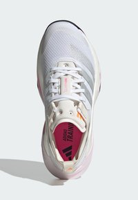 Białe buty sportowe z oddychającej siateczki, różowe akcenty na wkładce oraz teksturowana podeszwa zapewniająca przyczepność. Logo umieszczone na języku.