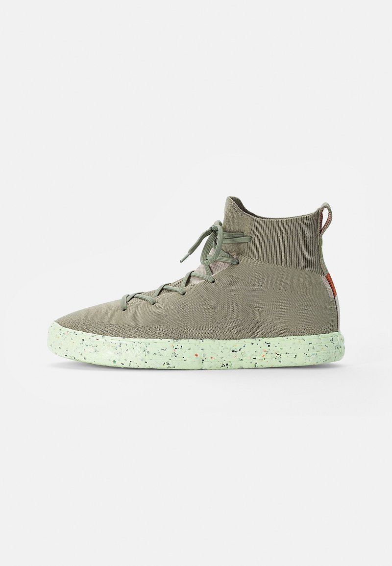 Basket montante tricotée en vert olive clair avec des lacets assortis et une semelle vert clair mouchetée sur fond blanc.