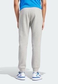 Grå sweatpants med elastiska avslut, gjorda av mjukt material, tillsammans med vita sneakers med blå accenter. Enkelt, strömlinjeformat design.