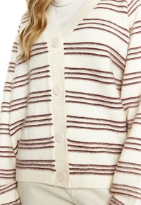 Cardigan crema con strisce orizzontali bordeaux, orlo a coste e due bottoni sul davanti. Texture morbida, vestibilità rilassata e design a V.