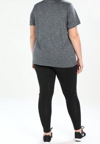 Camiseta deportiva gris de manga corta con un corte relajado, combinada con leggins negros que cuentan con un elegante patrón texturizado y una cintura elástica.