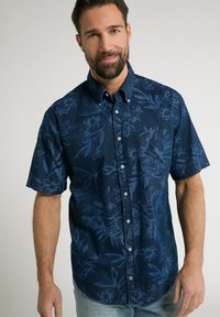 Korte mouwen, button-up shirt in donker marineblauw met een textuurpatroon van bloemen in lichter blauw. Heeft een borstzak en een kraag.