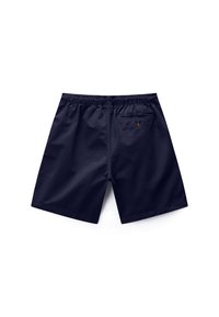 Μπλε σκούρο μαγιό βερμούδα με ελαστική μέση και μια πίσω τσέπη με κουμπί και πορτοκαλί λεπτομέρεια loop, εμφανίζεται απλωμένο σε λευκό φόντο.