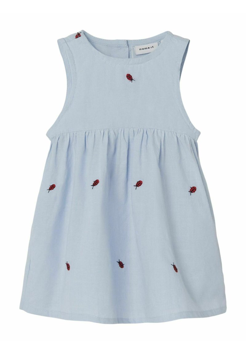 Lichtblauw katoenen jurk met een ronde hals en mouwloos ontwerp. Kenmerkt zich door rode geborduurde lieveheersbeestjes aan de voorkant en een gerimpelde taille.