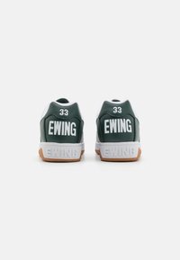 Zöld bőr sportcipők fehér részletekkel, nagyméretű fehér "EWING" felirattal és "33" számmal a sarkon, valamint gumis talppal.