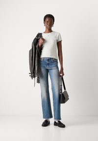 Gestreept lichtgroen T-shirt, zwart leren jasje, blauwe wijdere jeans, zwarte handtas en zwarte loafers. Eenvoudig, modern ontwerp.