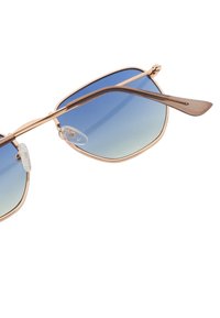 Aurinkolasit, joissa on ruusukultainen metallireunus, siniset gradienttilinssit ja kirkkaat nenätyynyt, esittelevät geometrista muotoilua ja siroja varsia.