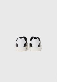 Fekete-fehér bőrsneaker sima felülettel, kontrasztos orr résszel és logóval a talpon. Lekerekített forma, alacsony szárú dizájn.