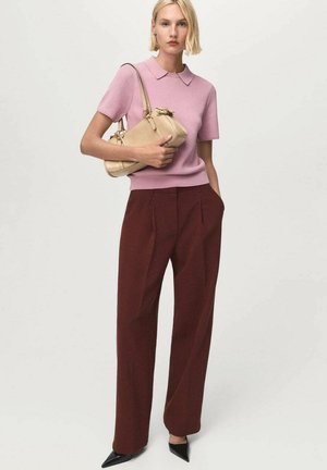 Light pink short-sleeve polo with a collar, paired with high-waisted maroon trousers and black pointed heels. Beige handbag with hardware details.