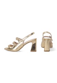 Gouden metallic slingback hakken met een blokhak, open teen en decoratieve gespaccenten op de banden. Gladde textuur met een glanzende afwerking.