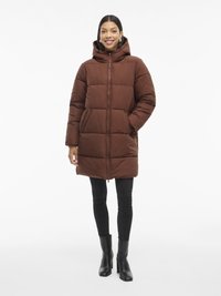 Cappotto piumino marrone con cappuccio, dotato di chiusura con zip, design trapuntato e tasche frontali. Abbinato a jeans skinny neri e stivali con tacco.