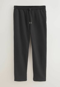 Zwarte joggingbroek van zachte stof, met een elastische tailleband en een trekkoord, en taps toelopende pijpen. Geen zichtbare zakken.