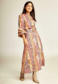 Abito lungo e colorato con un motivo paisley nelle tonalità di rosa, oro e blu. Presenta un colletto alto, maniche puff e una vita cinnecta.