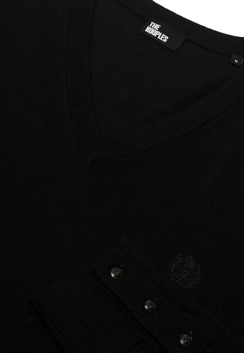 Pull noir en maille avec col en V et une poche comportant trois boutons noirs et un logo discret, fabriqué dans un tissu texturé doux.