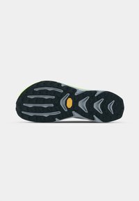 Semelle de chaussure de trail en noir et gris, avec des motifs de traction profonds et agressifs et un accent jaune mis en valeur. Marque Vibram visible.