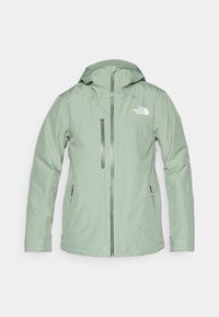 Chaqueta impermeable de material verde claro, con capucha, cierre frontal con cremallera y bolsillos laterales, con un logotipo en la parte superior izquierda del pecho.