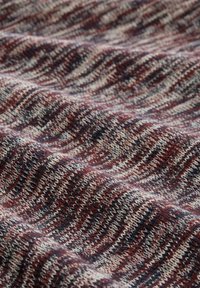 Stickad tyg i nyanser av burgundy och kräm med ett vågigt mönster, som visar en mjuk textur och medelvikt.