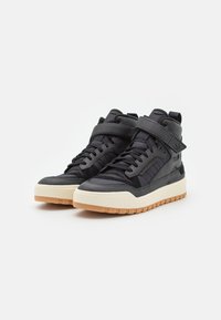 Svart högsko sneakers i texturerat material, med ett kardborreband, gummisula och kontrasterande gummisul.