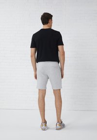 Svart kortermet skjorte og grå shorts. Antrekket er laget av bomull, med et enkelt design og atletisk stil. Sølv- og gullfargede joggesko.