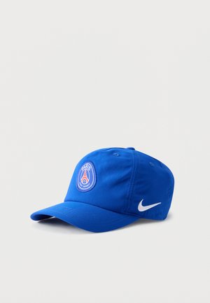 Niebieska czapka z daszkiem z logo Paris Saint-Germain z przodu i białym znakiem Nike z boku, na jednolitym tle.