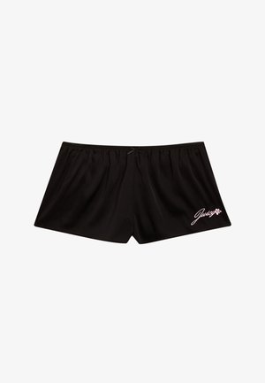 Pantaloni corti neri in satin con vita elasticizzata e vestibilità ampia. Presentano un logo rosa "Juicy" con accenti floreali in basso a destra.