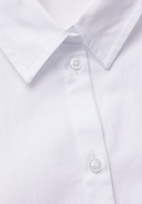 Camicia bianca in cotone con colletto classico e un singolo bottone trasparente sul collo. Texture liscia con dettagli di cucitura precisi.
