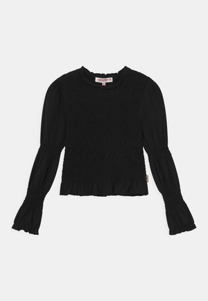 Blouse noire à manches longues avec corsage et manches smockés, encolure ronde à volants et poignets évasés.