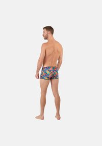 Simbyxor med ett färgglatt blommönster på en mörk bakgrund, med en figurnära passform och svart kant vid midjan.