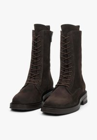 Brązowe zamszowe buty na sznurówki o gładkim wykończeniu, z bocznym zamkiem błyskawicznym, okrągłym noskiem i masywną gumową podeszwą zapewniającą trwałość.